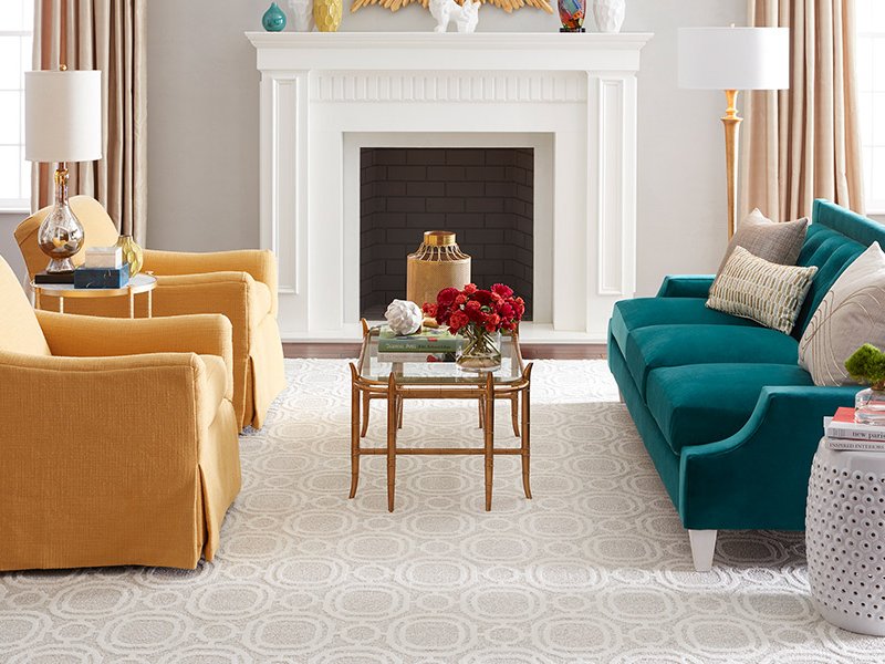 green couch and two yellow armchairs in front of a fireplace and on beige carpet floor from Beseda Flooring Saint Charles, MO